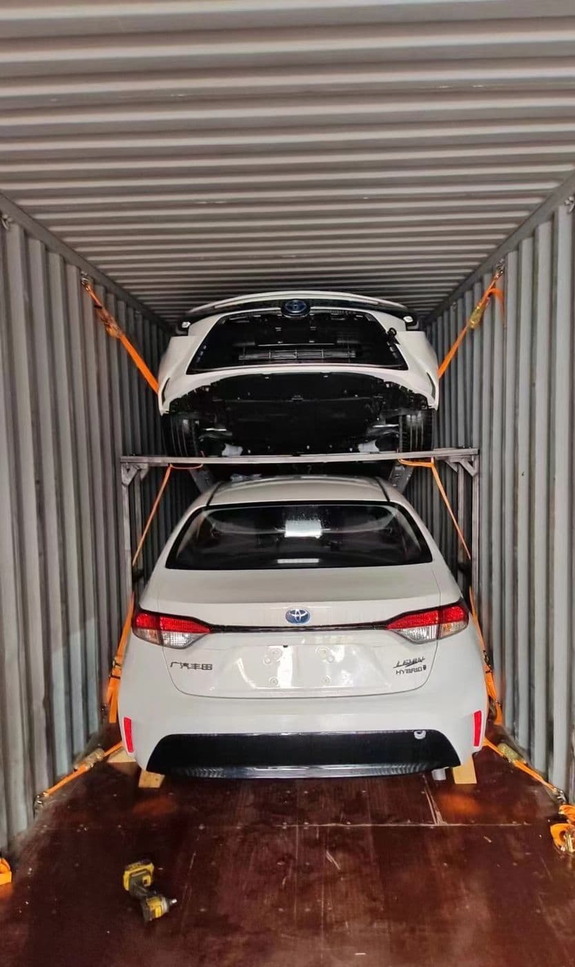 Two cars double-stacked on a rack inside a container